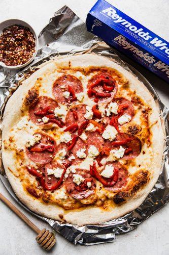 Grilled Pizza is a layered traditional pizza with a soft cheese combination, a little spice, thin cut salami topping all sweetened up by honey drizzled over top